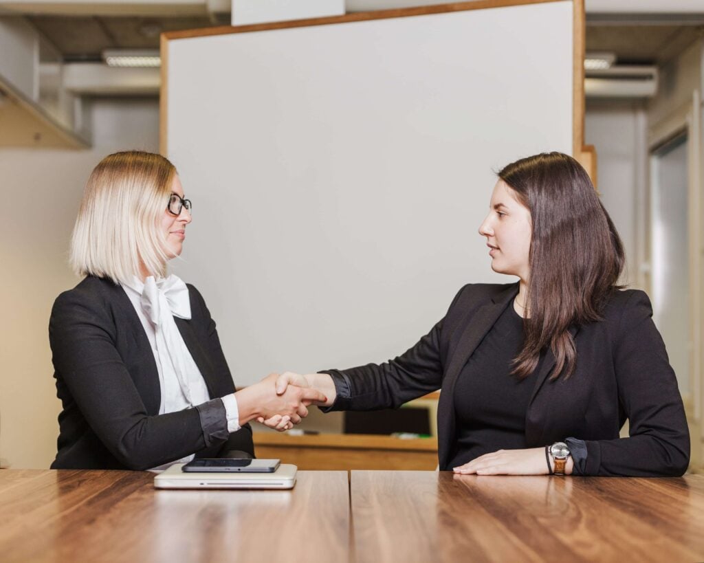 Two women shaking hands and using phrases in Dutch to show good manners