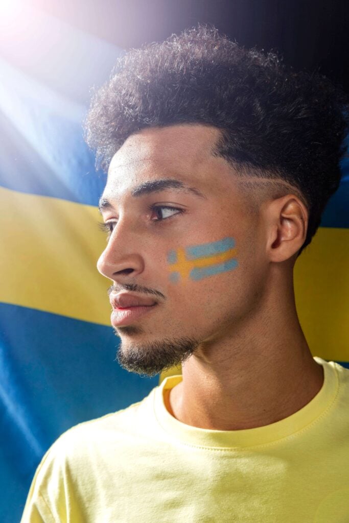 Swedish young man with the Swedish flag behind and on his cheek